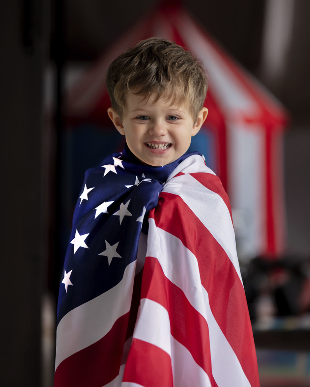 Menino sorrindo enrolado na bandeira dos Estados Unidos